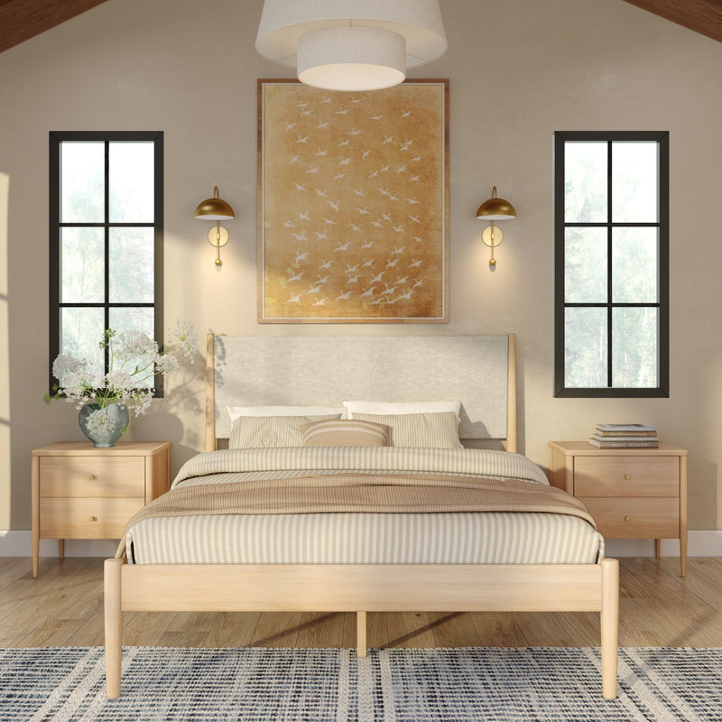 Modern minimalist bedroom with light wood platform bed, striped beige bedding, matching nightstands, gold wall sconces, framed bird artwork and tall black-framed windows