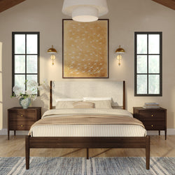 Modern mid-century bedroom with wooden platform bed, beige striped bedding, upholstered headboard, matching dark wood nightstands, brass wall sconces, large abstract bird wall art, tall black-framed windows, hardwood floor and patterned rug