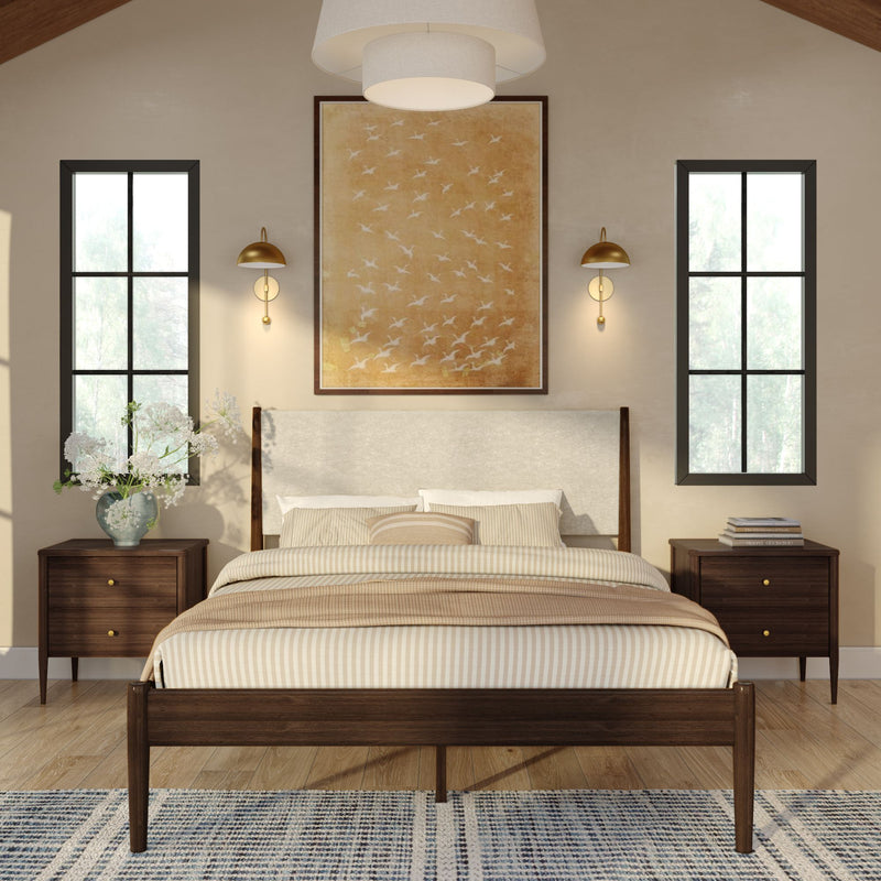 Modern mid-century bedroom with wooden platform bed, beige striped bedding, upholstered headboard, matching dark wood nightstands, brass wall sconces, large abstract bird wall art, tall black-framed windows, hardwood floor and patterned rug