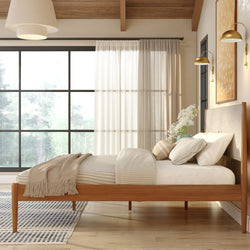 Modern Scandinavian bedroom with wooden platform bed, neutral bedding and throw, large black-framed window with sheer curtains and natural light