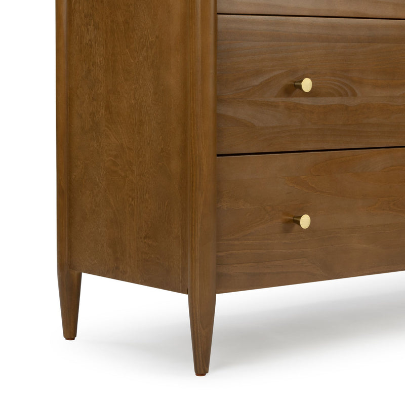 Close-up of mid-century modern walnut dresser with tapered legs, brass drawer knobs and natural wood grain finish