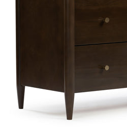 Dark walnut dresser close-up showing mid-century modern tapered legs, two drawers with round brass knobs — bedroom furniture detail