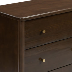 Close-up of dark walnut wooden dresser with smooth beveled edge and brass round knobs, modern mid-century bedroom storage furniture