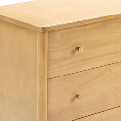Close-up of minimalist light wood dresser with natural pine finish and brass round drawer knobs, modern bedroom storage furniture