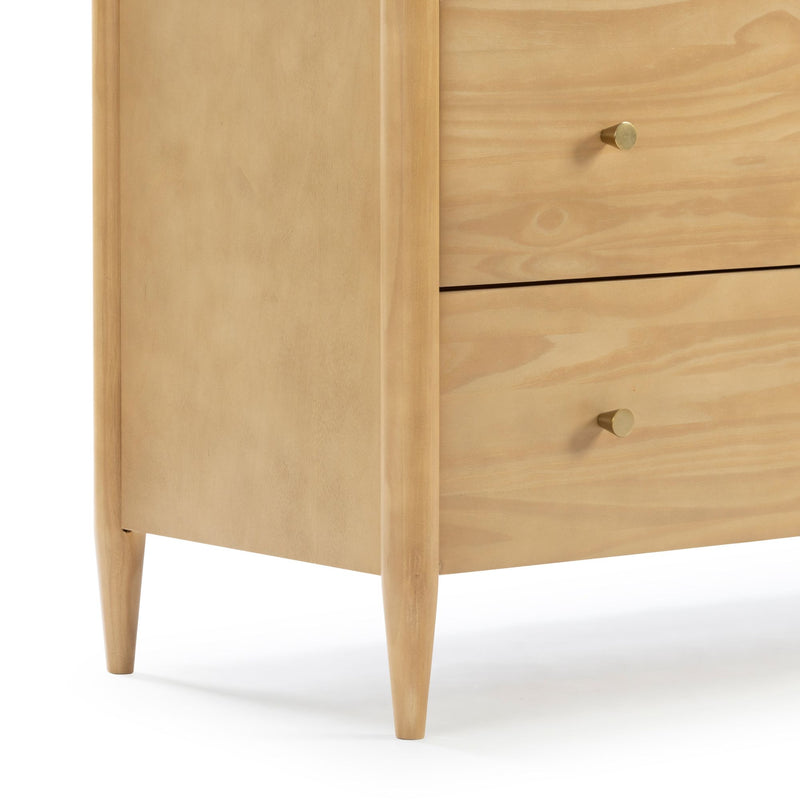 Mid-century modern light wood dresser corner showing two drawers with brass knob pulls and tapered legs — bedroom storage furniture