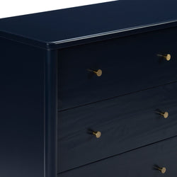 Close-up of navy blue painted wooden dresser with round brass knobs, modern bedroom storage chest