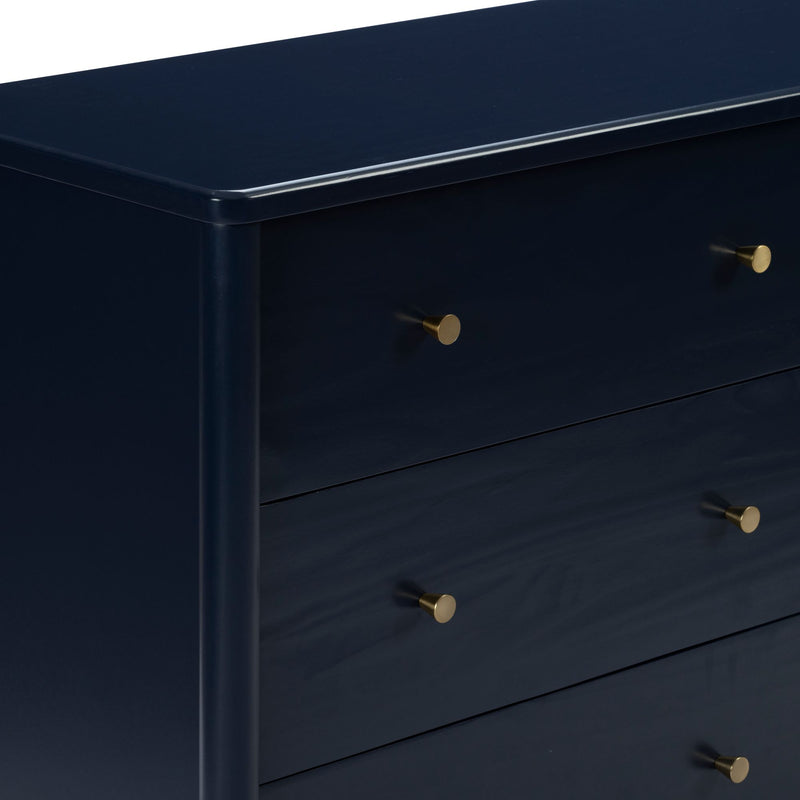 Close-up of navy blue painted wooden dresser with round brass knobs, modern bedroom storage chest