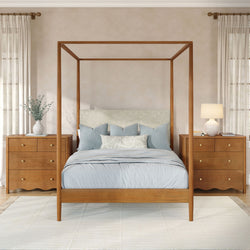 Wooden four‑poster canopy bed in a neutral modern farmhouse bedroom with light blue bedding, matching wooden nightstands with brass knobs, ceramic table lamps, eucalyptus vase and sheer curtains