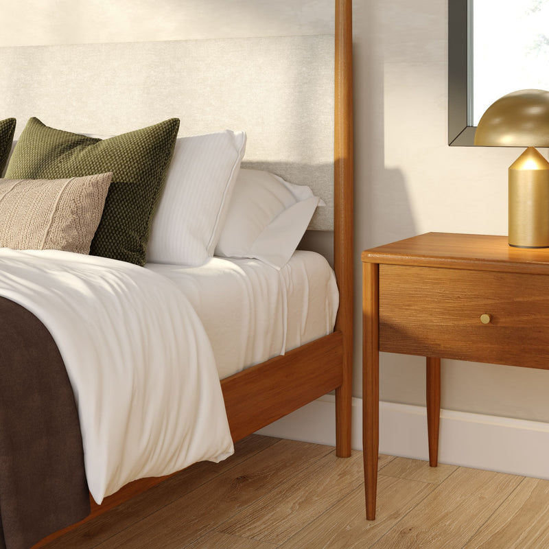 Mid-century modern bedroom corner with wooden bed frame and upholstered headboard, white bedding, green textured pillows, hardwood floor and wood nightstand with brass lamp