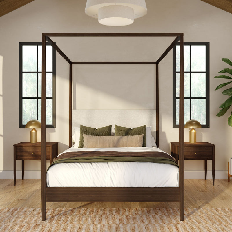 Modern bedroom interior with dark wood four-poster bed, white bedding and green accent pillows, matching wood nightstands with gold lamps, black-framed windows and hardwood floor