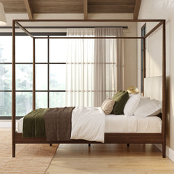 Modern bedroom with wooden four-poster bed, white bedding, green accent pillows and brown throw, sheer floor-to-ceiling window and natural light