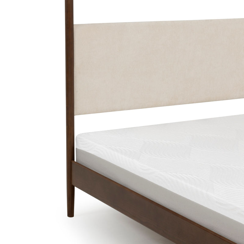 Close-up of mid-century modern walnut wood bed frame with beige upholstered headboard and white mattress on white background