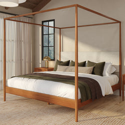 Modern wooden four-poster canopy bed in a neutral farmhouse bedroom with white linens, olive throw pillows, wooden nightstands and natural light