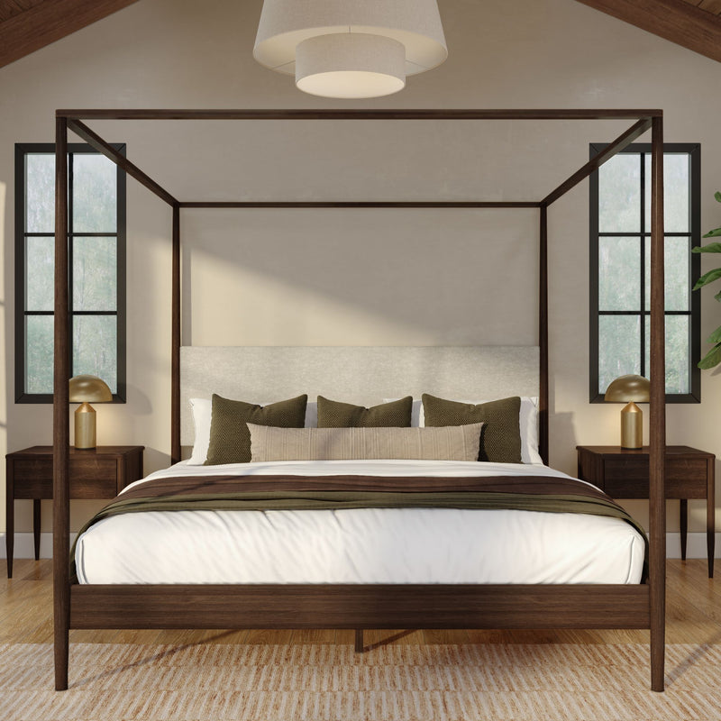 Modern wooden four-poster canopy bed in a neutral master bedroom with linen bedding, green accent pillows, brass bedside lamps, and black-framed windows