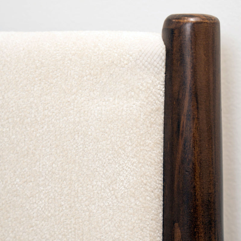 Beige upholstered headboard close-up showing fabric texture and dark walnut wood post, modern bedroom furniture detail
