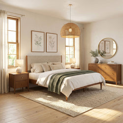 Cozy neutral modern bedroom with wooden bed and dresser, woven rattan pendant light, framed botanical prints, round mirror, textured rug and natural light