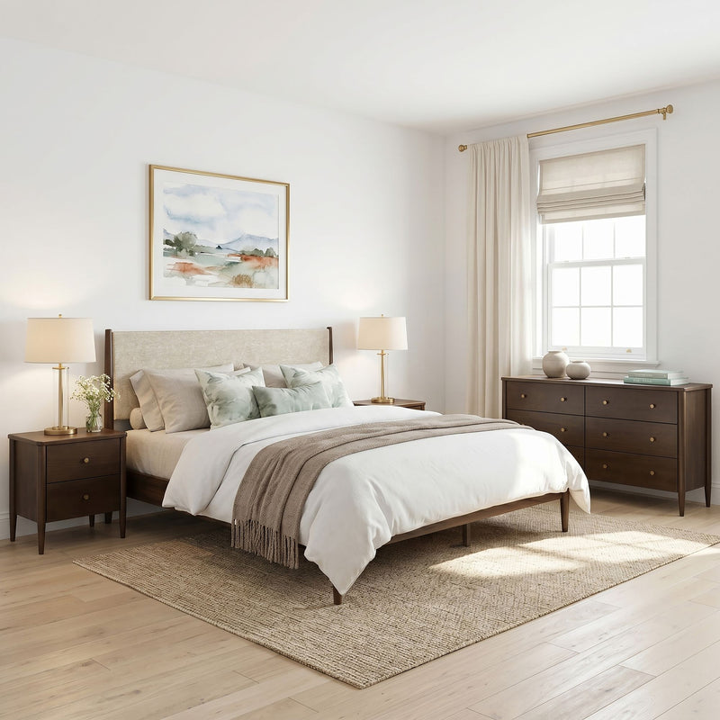 Neutral modern bedroom with upholstered wood bedframe, neutral bedding, light hardwood floors, natural fiber rug, brass lamps, dresser and roman shade window