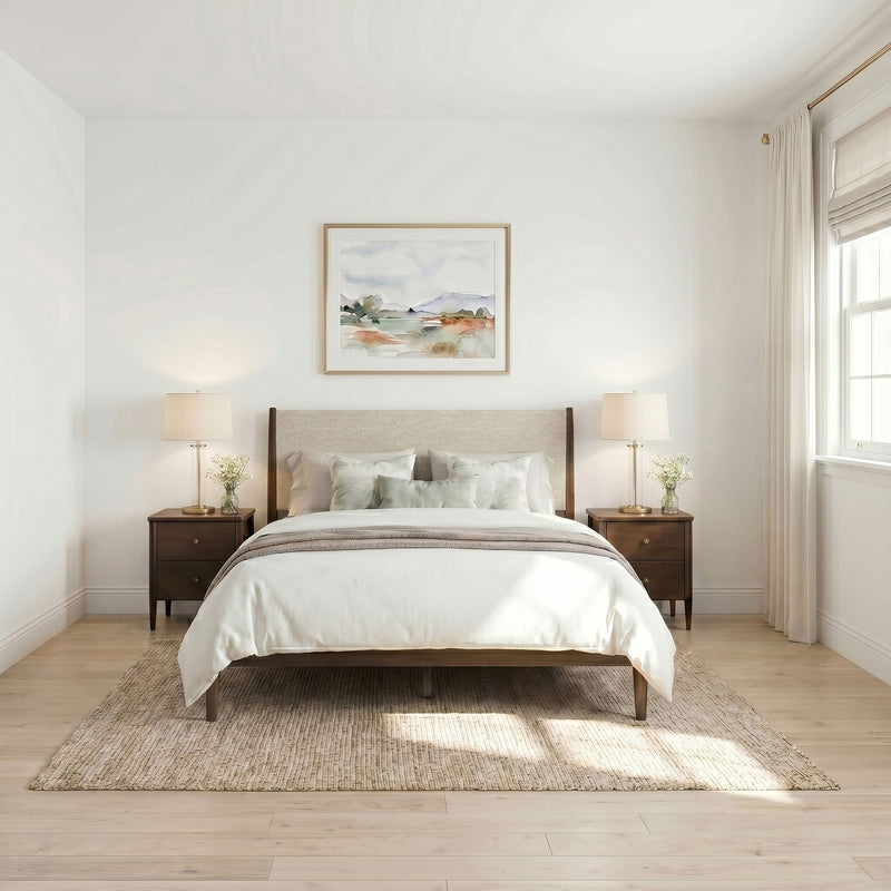 Modern minimalist bedroom interior with upholstered headboard, neutral bedding, wooden nightstands, matching table lamps, watercolor wall art, sheer curtains and light hardwood floors.