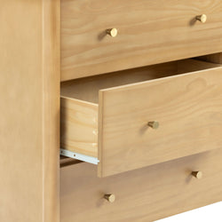 Close-up of natural pine dresser drawers with brass knobs and one open drawer