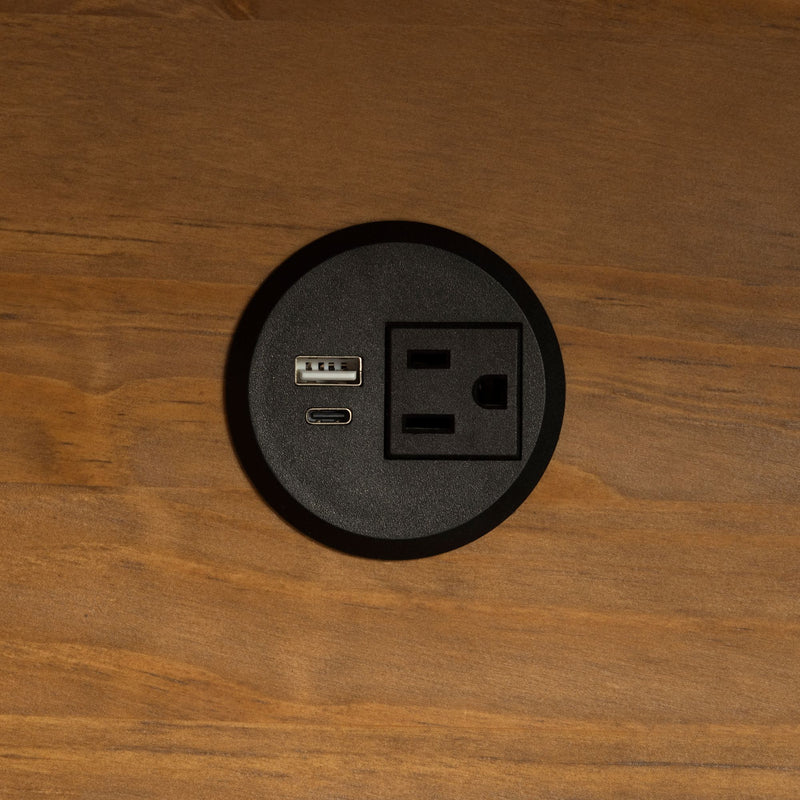 A close-up of a black electric socket with a USB-A port, USB-C port, and standard American socket. 