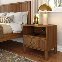Modern cozy bedroom close-up with wooden slatted headboard, wooden nightstand with built-in charging port, brass dome lamp, framed art and neutral bedding
