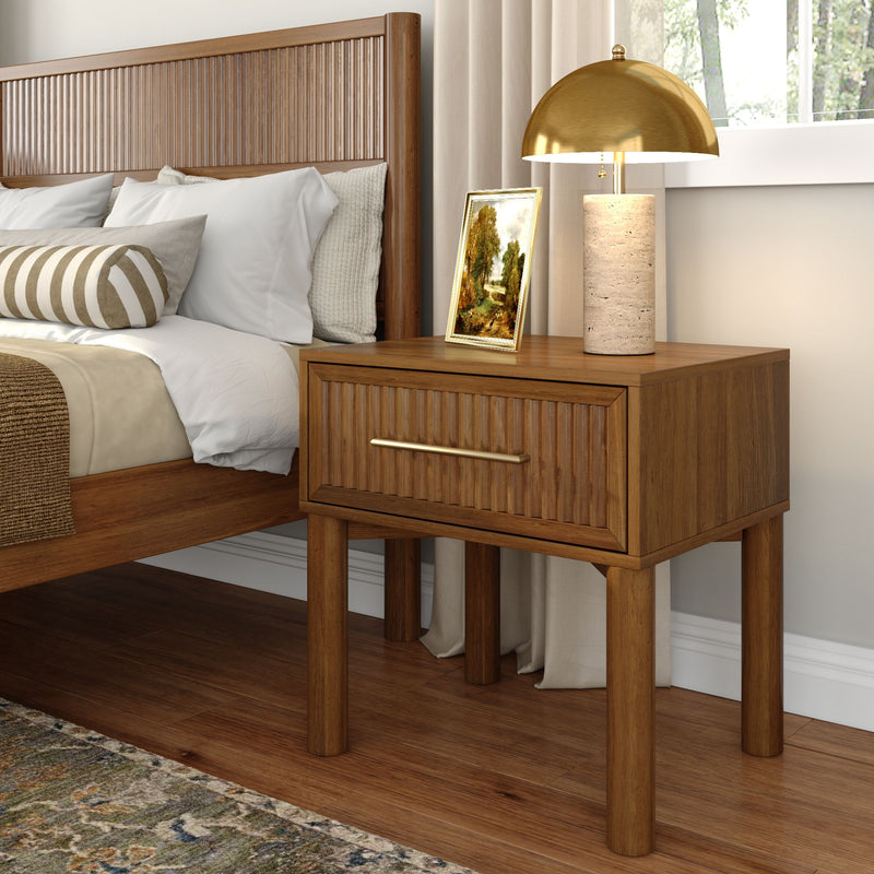 Walnut wooden nightstand with brass dome table lamp and stone base, textured slatted headboard, white bedding and striped bolster pillow in a cozy modern bedroom