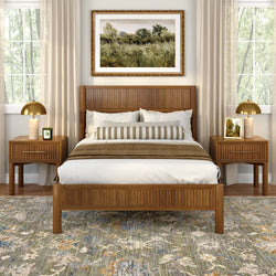 Mid-century modern wooden bed in a neutral master bedroom with striped bolster pillow, matching nightstands and brass lamps, landscape wall art and patterned area rug