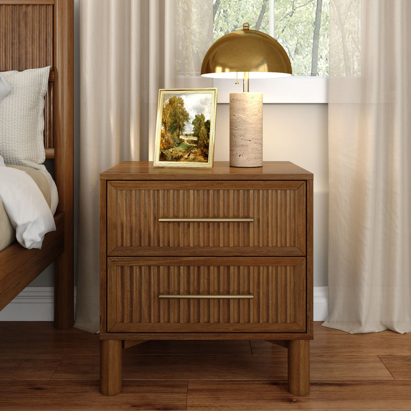 Wooden nightstand with ribbed drawers topped by a stone-base table lamp with gold dome shade and a framed landscape painting, next to a wooden bed and beige curtains — cozy modern bedroom decor