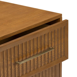 Close-up of wooden dresser drawer with ribbed carved front and brass bar handle, warm oak finish