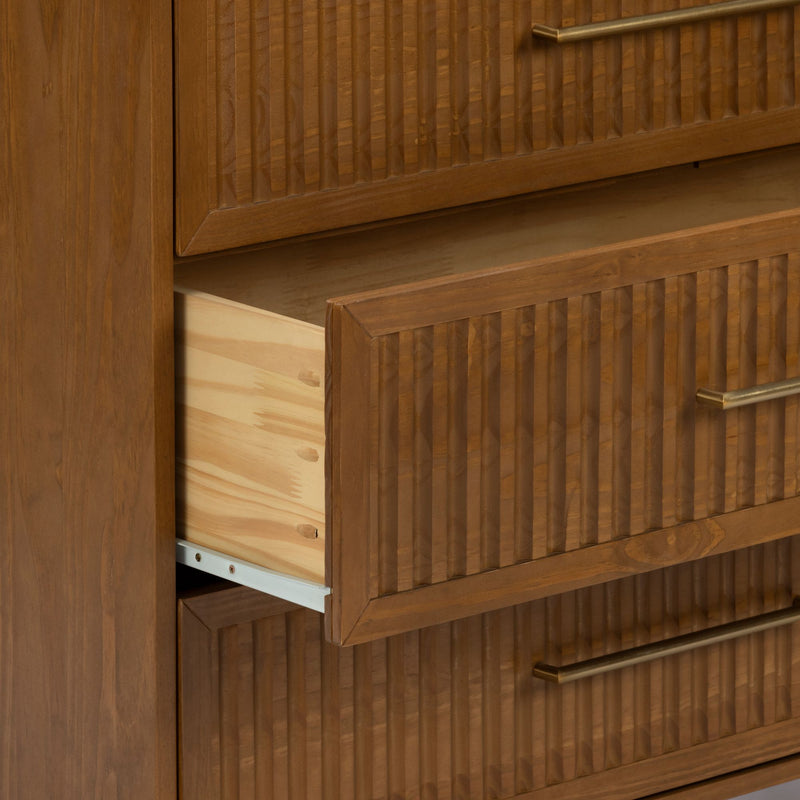 Close-up of mid-century modern solid wood dresser with fluted drawer fronts and brass handles, showing an open pine interior drawer on metal slides