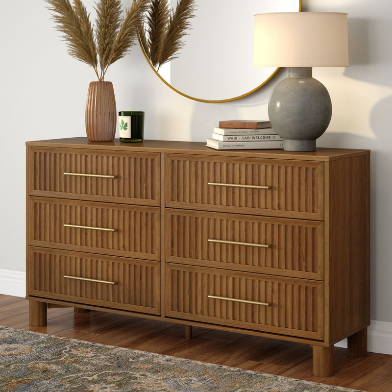 Mid-century modern six-drawer walnut dresser with brass handles, round wall mirror, ceramic lamp, decorative vase and books on hardwood floor