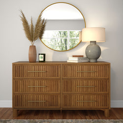Natural wood six-drawer dresser with fluted fronts and brass handles styled with round gold-framed mirror, gray ceramic table lamp, terracotta vase with pampas grass and scented candle, modern entryway decor