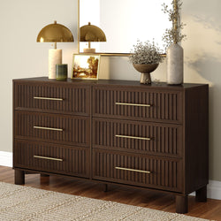 Mid-century modern six-drawer walnut bedroom dresser with ribbed drawer fronts and brass handles, styled with gold dome lamp, framed art, mirror and vase on hardwood floor