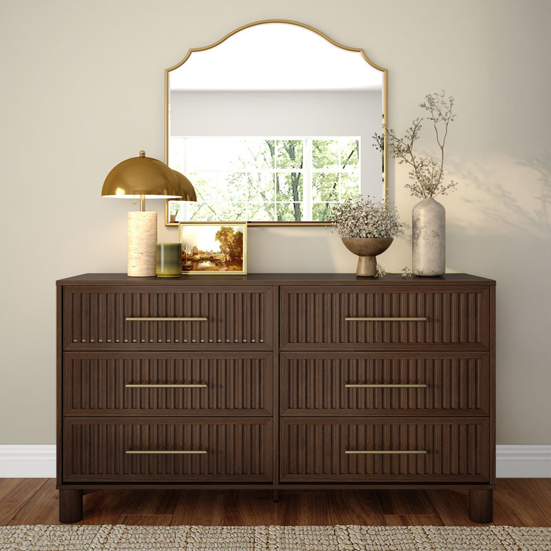Dark wood six-drawer dresser with gold-framed mirror, brass lamp, framed picture and ceramic vases styled for neutral entryway or bedroom decor