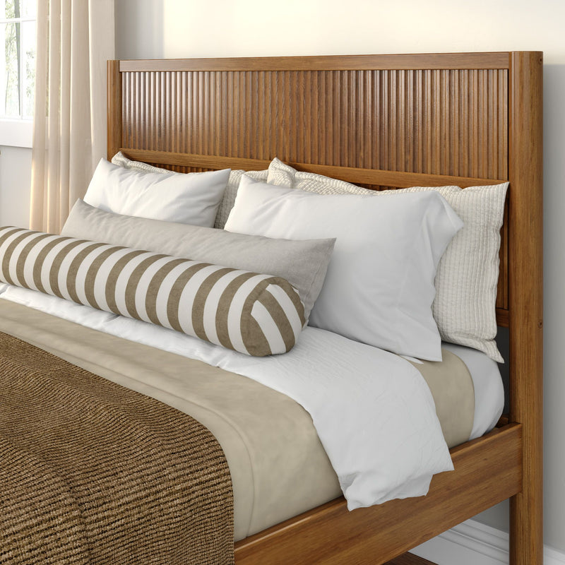 Wooden slatted headboard bed with beige and white bedding, white pillows and a striped bolster pillow