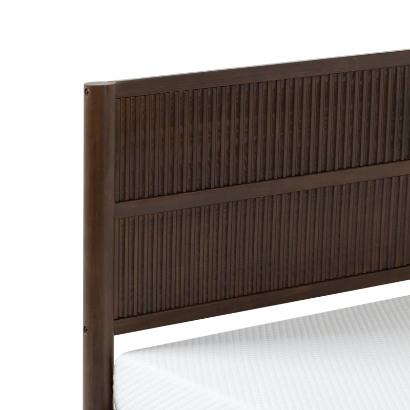 Close-up of dark brown solid wood headboard with vertical ribbed slats on bed frame and white mattress