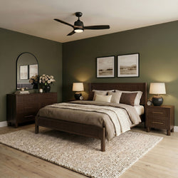 Modern bedroom with wooden bed frame, ceiling fan with integrated light, matching nightstands and dresser, neutral bedding and woven rug on olive‑green walls