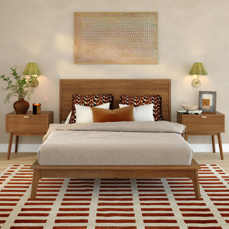 Mid-century modern bedroom with wood platform bed, neutral linens, patterned accent pillows, matching wood nightstands, wall sconces, and red-striped area rug