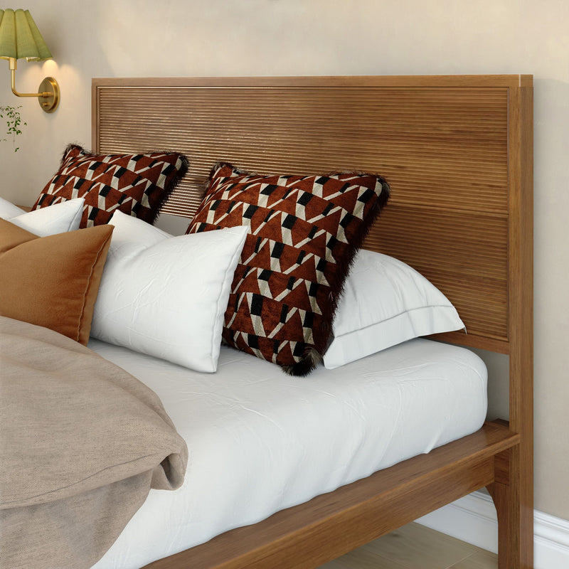 Modern wooden bed with slatted headboard, white bedding and brown geometric decorative pillows in cozy neutral bedroom decor.