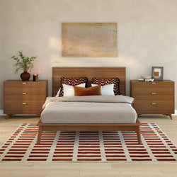 Mid-century modern bedroom with wooden platform bed and matching walnut nightstands, neutral linen bedding, rust-and-white geometric area rug, patterned throw pillows and minimalist wall art