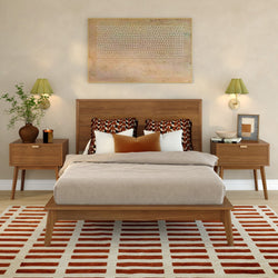 Mid-century modern bedroom with wood platform bed, neutral linen bedding, geometric throw pillows, matching wood nightstands and wall sconces, abstract wall art, potted plant, and red-and-white striped area rug