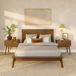 Neutral modern bedroom with wooden platform bed, patterned pillows, mid-century nightstands, green wall sconces, framed art and potted plant