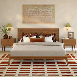 Mid-century modern bedroom with wood platform bed, neutral linen bedding, geometric throw pillows, matching wooden nightstands, green wall sconces, abstract wall art, potted plant and red-striped area rug