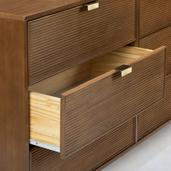 Mid-century modern wooden dresser with ribbed drawer fronts and brass handles, open drawers showing light pine interiors