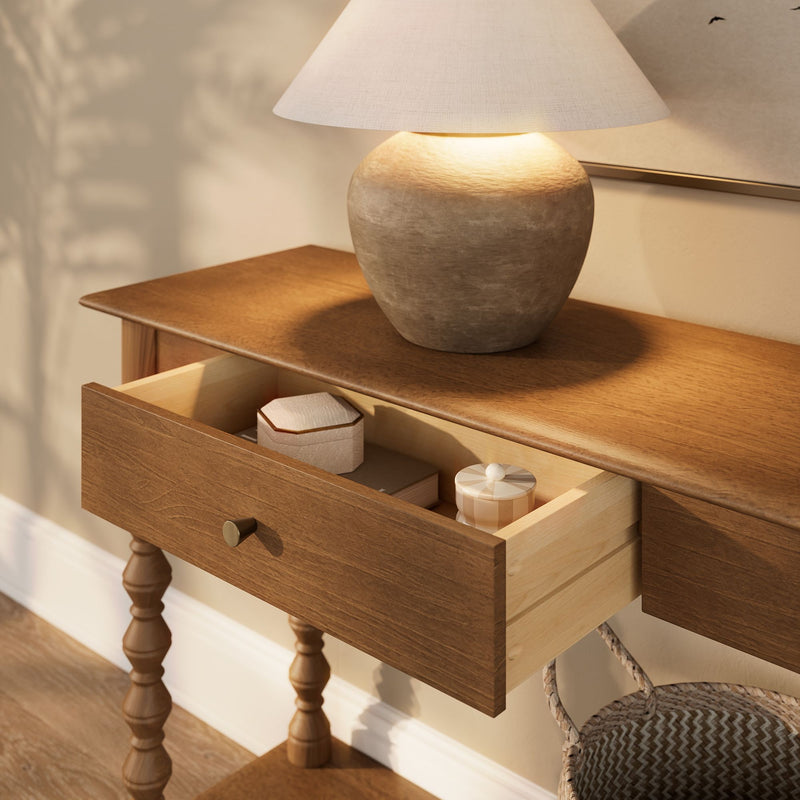 Ceramic table lamp with linen shade on wooden nightstand, open drawer with decorative boxes — cozy neutral bedroom lighting
