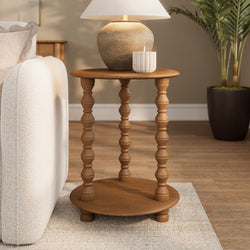 Wooden round side table with turned legs, rustic ceramic lamp and white candle next to a beige sofa in a neutral cozy living room