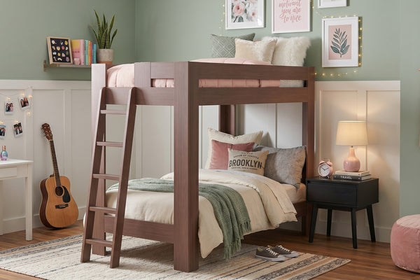 Modern wooden loft bed with ladder in a pastel green and pink teen bedroom, styled with cozy bedding, decorative pillows, nightstand lamp, acoustic guitar and framed wall art