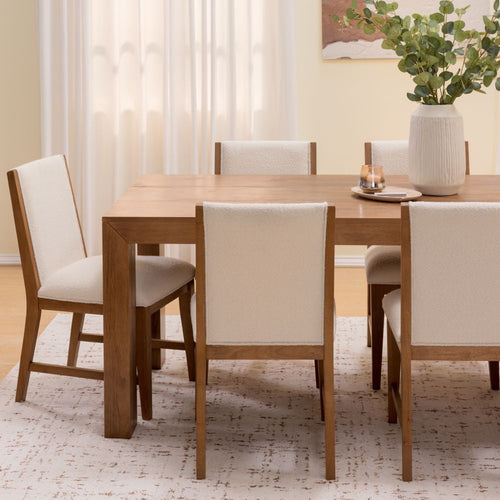 Modern 6-seat solid wood dining table with cream upholstered chairs, neutral rug, eucalyptus vase and candle in a bright minimalist dining room