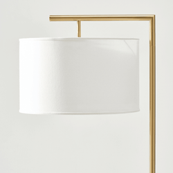 Modern gold floor lamp with white drum shade.