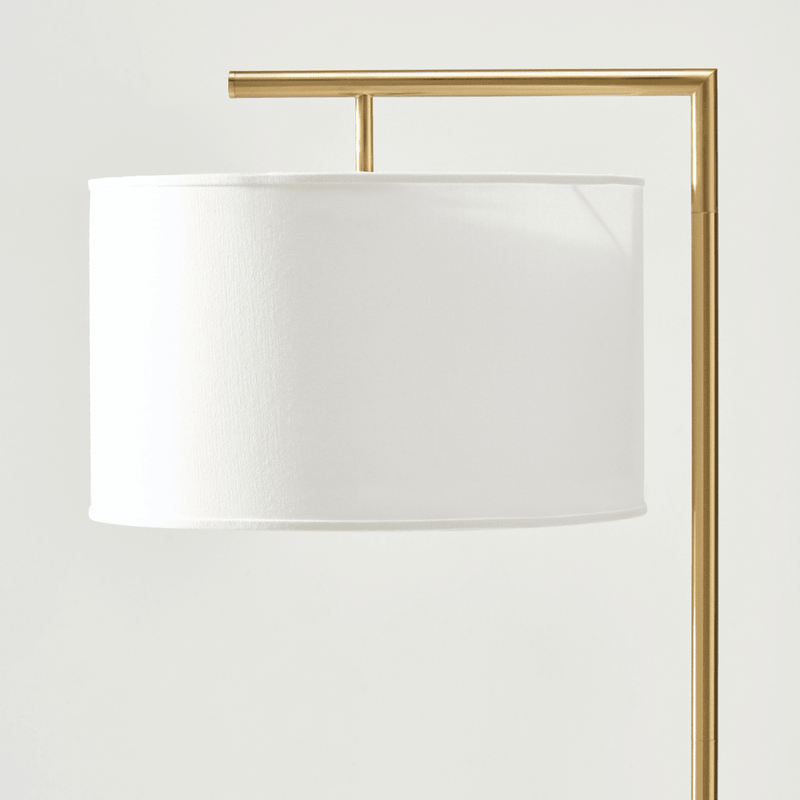 Modern gold floor lamp with white drum shade.